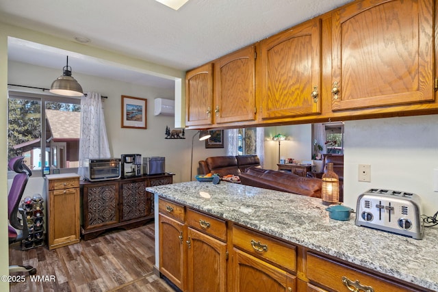 kitchen featuring an AC wall unit, hanging light fixtures, dark wood-type flooring, and brown cabinets