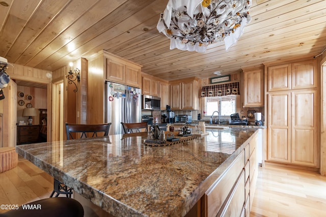 kitchen featuring a breakfast bar, light wood-style flooring, a sink, wood ceiling, and appliances with stainless steel finishes