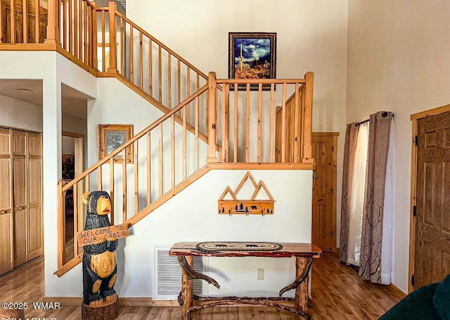 stairs featuring visible vents, a high ceiling, and wood finished floors