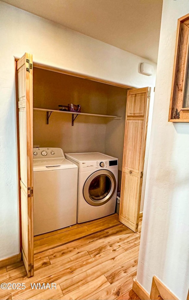 laundry room with laundry area, separate washer and dryer, light wood-type flooring, and baseboards