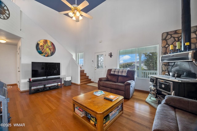 living area with high vaulted ceiling, a wealth of natural light, and a wood stove