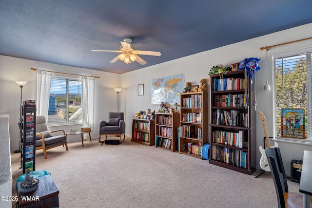 sitting room with a ceiling fan and carpet flooring