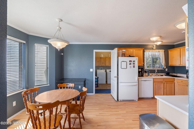 kitchen with light countertops, light wood-style floors, ornamental molding, white appliances, and washer and clothes dryer