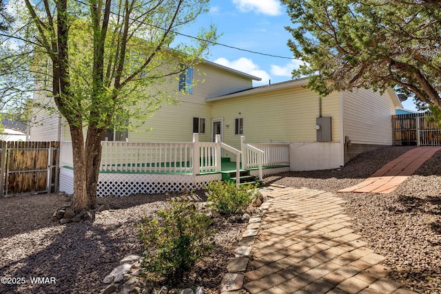 rear view of house featuring fence and a deck