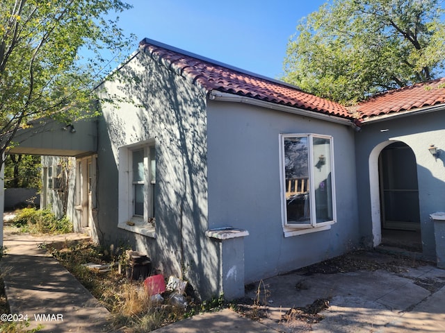 view of property exterior with a tile roof and stucco siding