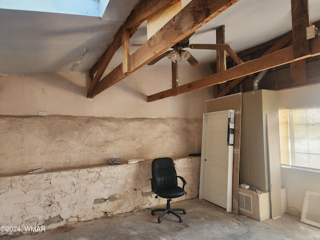 interior space featuring a skylight, beam ceiling, and unfinished concrete floors