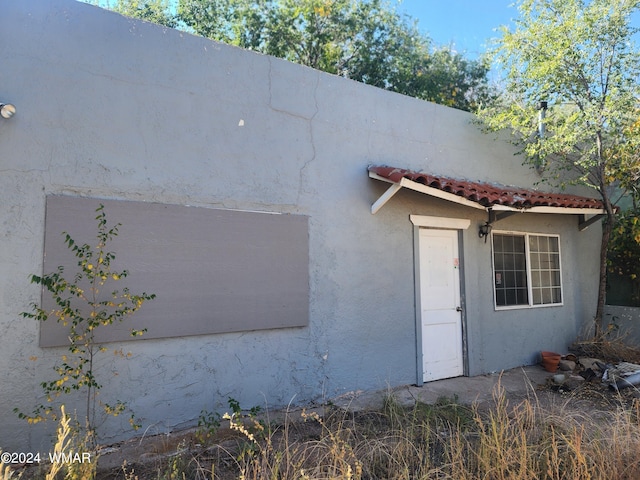 exterior space featuring a tiled roof and stucco siding