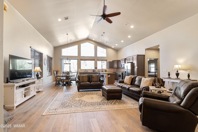 living room featuring ceiling fan, high vaulted ceiling, light wood-type flooring, and visible vents