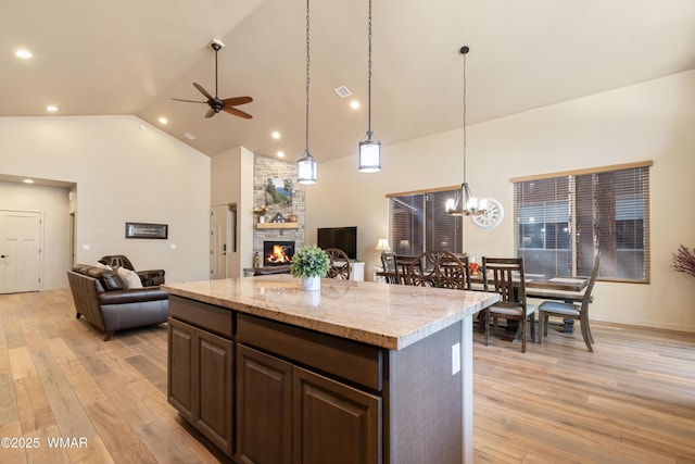 kitchen featuring open floor plan, high vaulted ceiling, light wood finished floors, and a fireplace