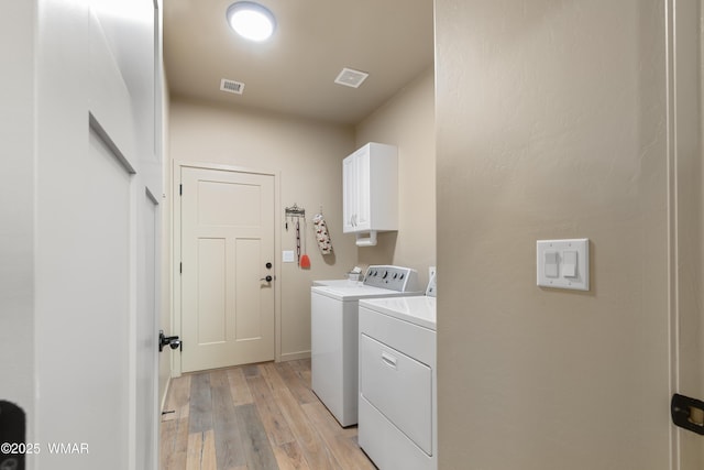 laundry room featuring visible vents, separate washer and dryer, light wood finished floors, and cabinet space