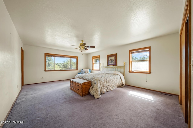 carpeted bedroom featuring ceiling fan, multiple windows, and baseboards