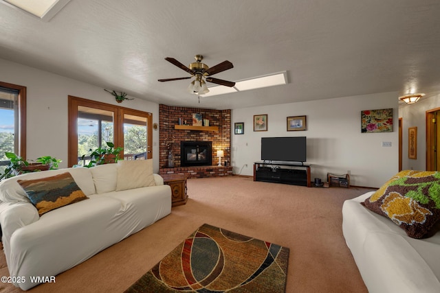 living room featuring carpet floors, a brick fireplace, ceiling fan, and a textured ceiling