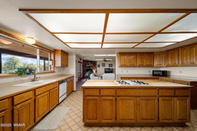 kitchen featuring white appliances, a kitchen island, a sink, brown cabinets, and light floors