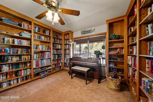 living area featuring ceiling fan, carpet floors, and bookshelves