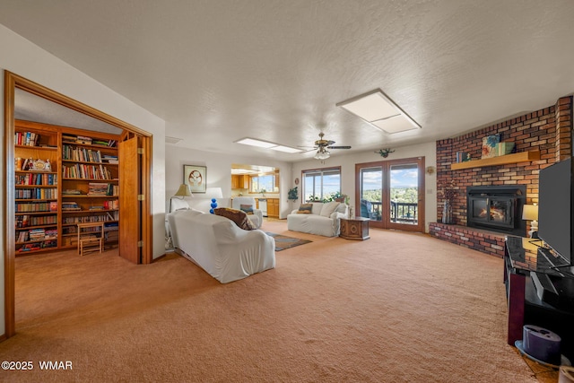 carpeted living room featuring ceiling fan, a fireplace, and a textured ceiling