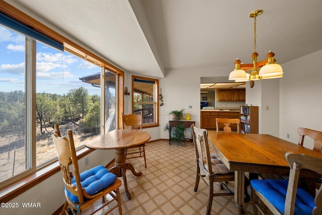 dining space with baseboards, light floors, and an inviting chandelier