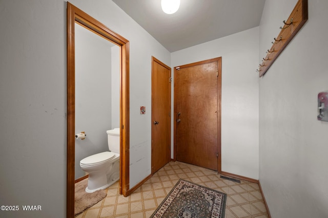 bathroom featuring toilet, baseboards, visible vents, and tile patterned floors