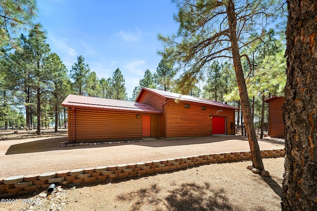 2722 Covered Wagon Trl, Overgaard, AZ 85933 - view of home's exterior featuring faux log siding, a metal roof, driveway, and a garage