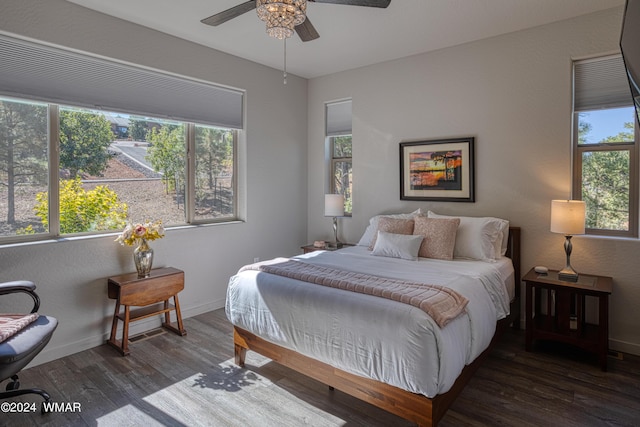 bedroom with dark wood-type flooring, a ceiling fan, and baseboards