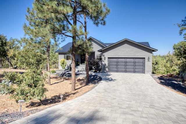 ranch-style home with a garage and decorative driveway