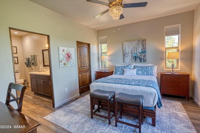 bedroom with light wood-type flooring, ensuite bath, and baseboards