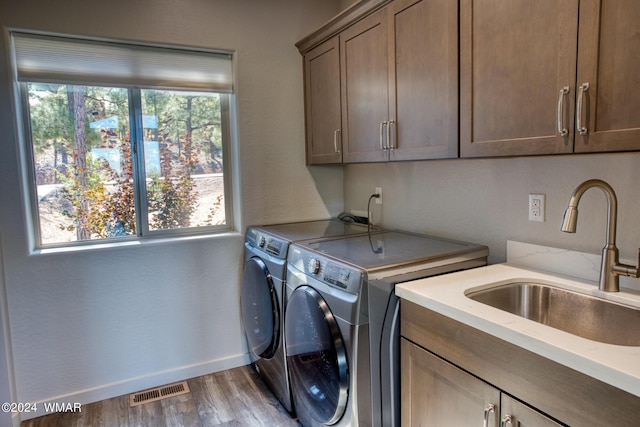 clothes washing area with cabinet space, visible vents, a sink, wood finished floors, and independent washer and dryer