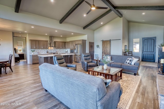 living room with light wood-style floors, a barn door, high vaulted ceiling, and beam ceiling