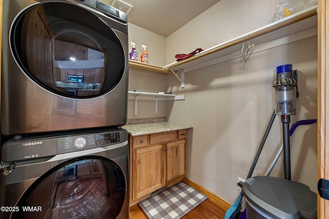 2190 Evergreen Ln, Show Low, AZ 85901 - washroom with stacked washing machine and dryer, light wood-type flooring, cabinet space, and baseboards