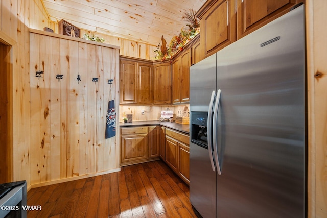4683 Eagle Nest Ct, Lakeside, AZ 85929 - kitchen featuring stainless steel fridge with ice dispenser, dark wood finished floors, brown cabinetry, wood walls, and dark countertops
