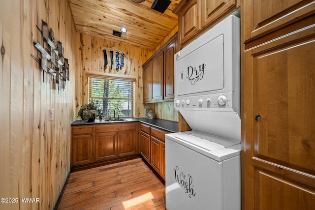 4683 Eagle Nest Ct, Lakeside, AZ 85929 - laundry area featuring stacked washing machine and dryer, light wood-style floors, wooden walls, cabinet space, and wood ceiling