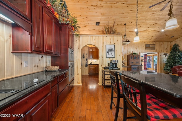4683 Eagle Nest Ct, Lakeside, AZ 85929 - kitchen featuring reddish brown cabinets, dark wood finished floors, wooden walls, arched walkways, and hanging light fixtures