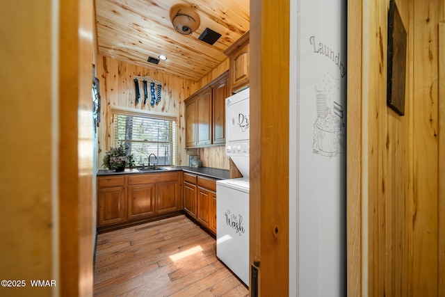 4683 Eagle Nest Ct, Lakeside, AZ 85929 - kitchen with stacked washer / dryer, brown cabinetry, light wood-style floors, wooden ceiling, and dark countertops