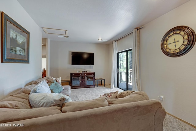 carpeted living room featuring attic access and baseboards