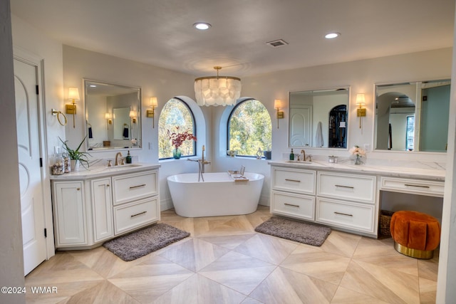 bathroom with a freestanding tub, recessed lighting, a sink, two vanities, and visible vents