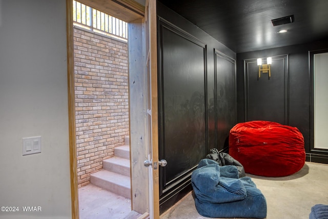 interior space with visible vents, concrete floors, and brick wall