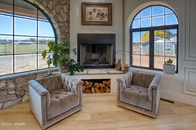 living area with light wood-type flooring, visible vents, and a fireplace with raised hearth