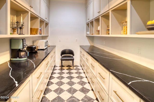 kitchen featuring white microwave, open shelves, built in study area, and tile patterned floors