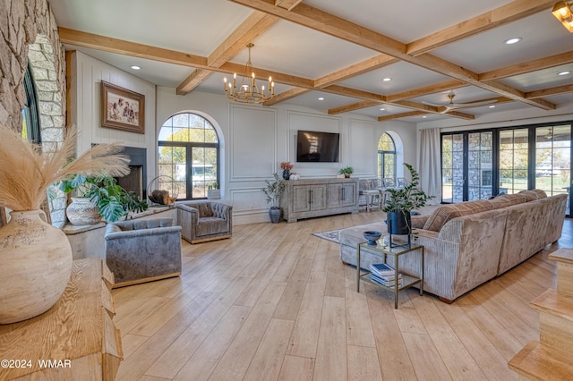 living area featuring beam ceiling, a notable chandelier, a decorative wall, light wood-type flooring, and coffered ceiling