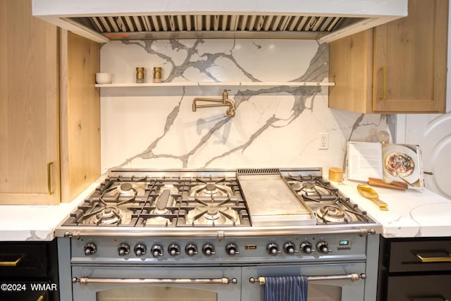 kitchen with decorative backsplash, light brown cabinetry, light stone countertops, double oven range, and extractor fan