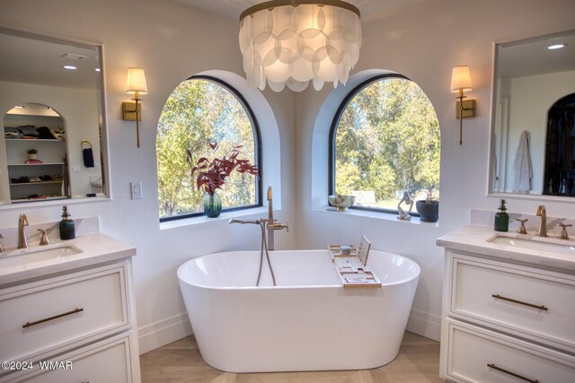 full bathroom featuring a freestanding tub, two vanities, and a sink