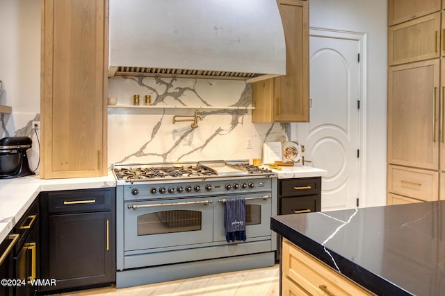 kitchen with light countertops, backsplash, dark cabinets, double oven range, and premium range hood