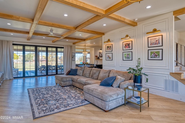 living room featuring visible vents, a decorative wall, light wood-type flooring, coffered ceiling, and stairs