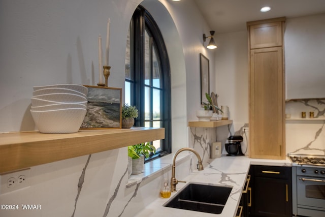 kitchen with range with gas stovetop, light countertops, dark cabinetry, a sink, and recessed lighting