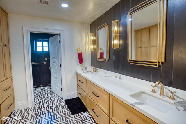 bathroom with double vanity, wooden walls, visible vents, and a sink