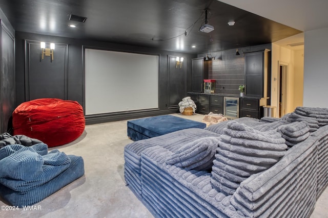 cinema featuring beverage cooler, a decorative wall, a dry bar, and unfinished concrete floors