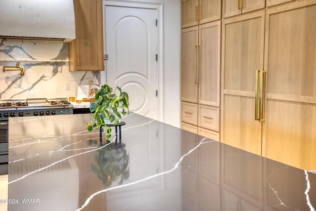 kitchen featuring premium range hood, stove, stainless steel counters, light brown cabinetry, and tasteful backsplash