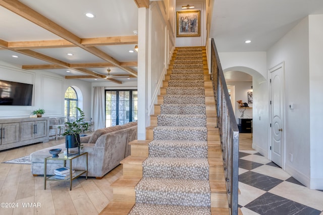 stairway with arched walkways, recessed lighting, coffered ceiling, baseboards, and beam ceiling