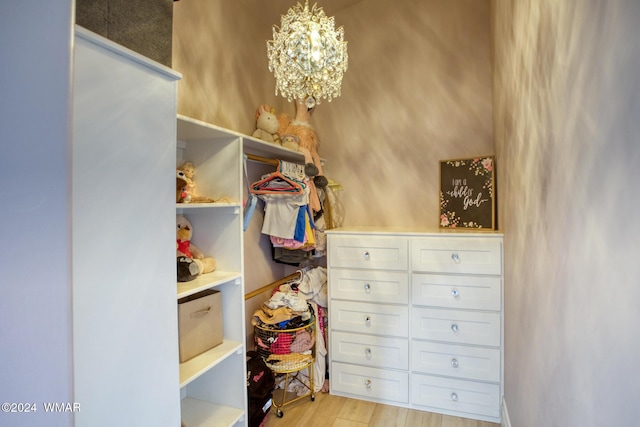 spacious closet with a chandelier and light wood-style flooring