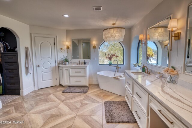 full bath featuring a freestanding bath, visible vents, a closet, and vanity