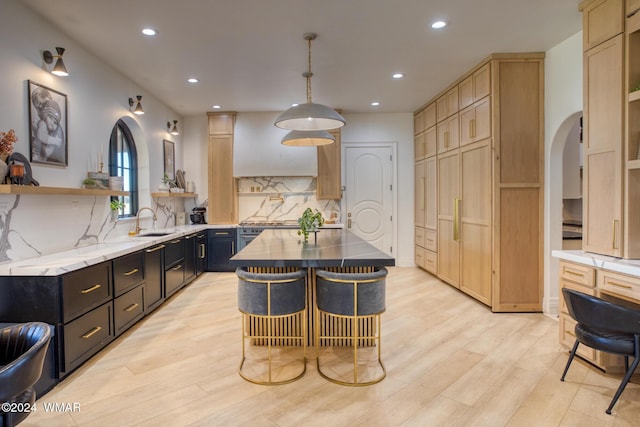 kitchen with a center island, decorative light fixtures, open shelves, dark cabinets, and a kitchen bar